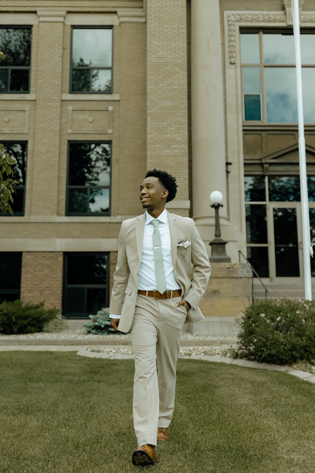 Joel Ngorimo walking outside a courthouse in a tan suit