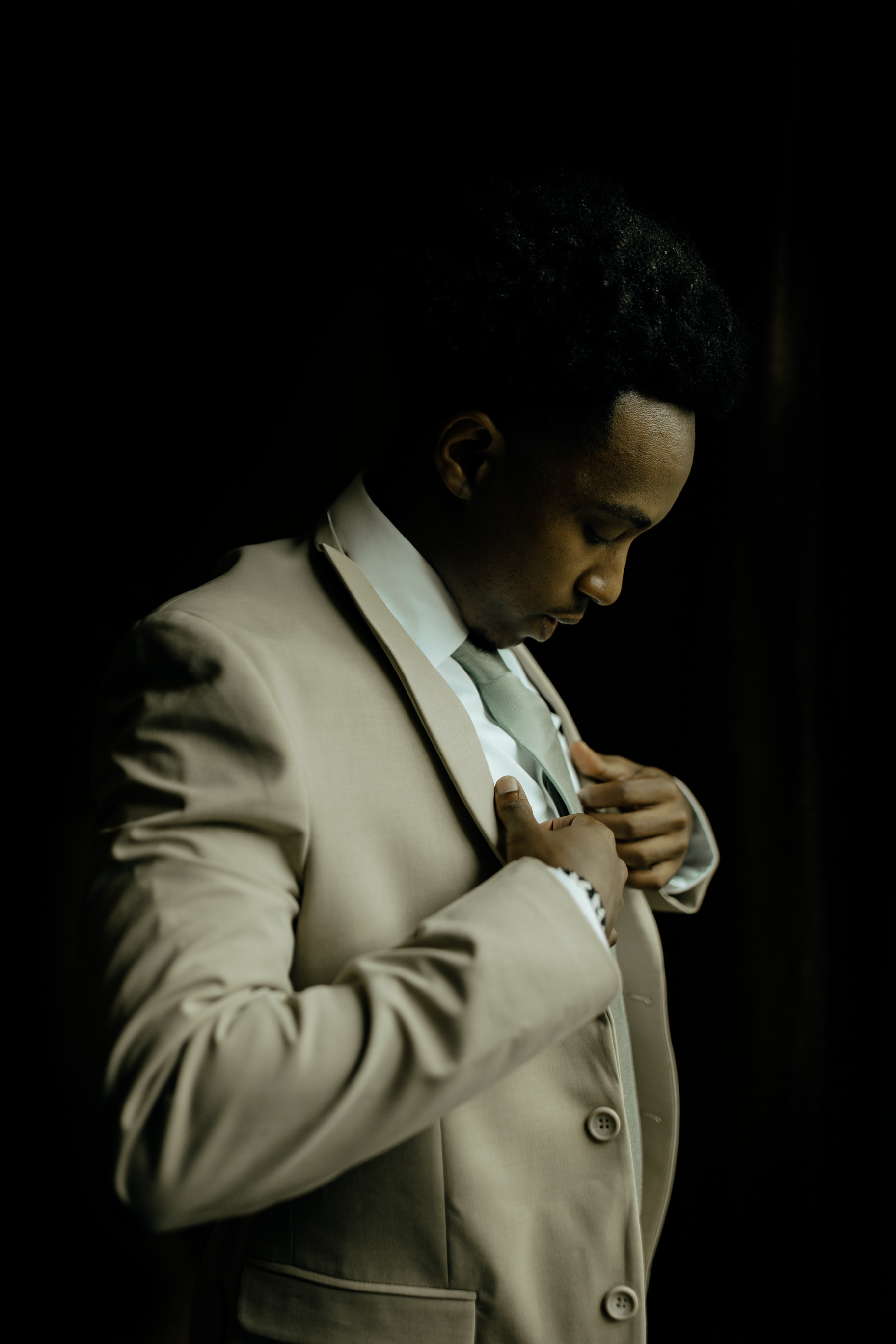 Joel Ngorimo adjusting his suit jacket in a studio portrait